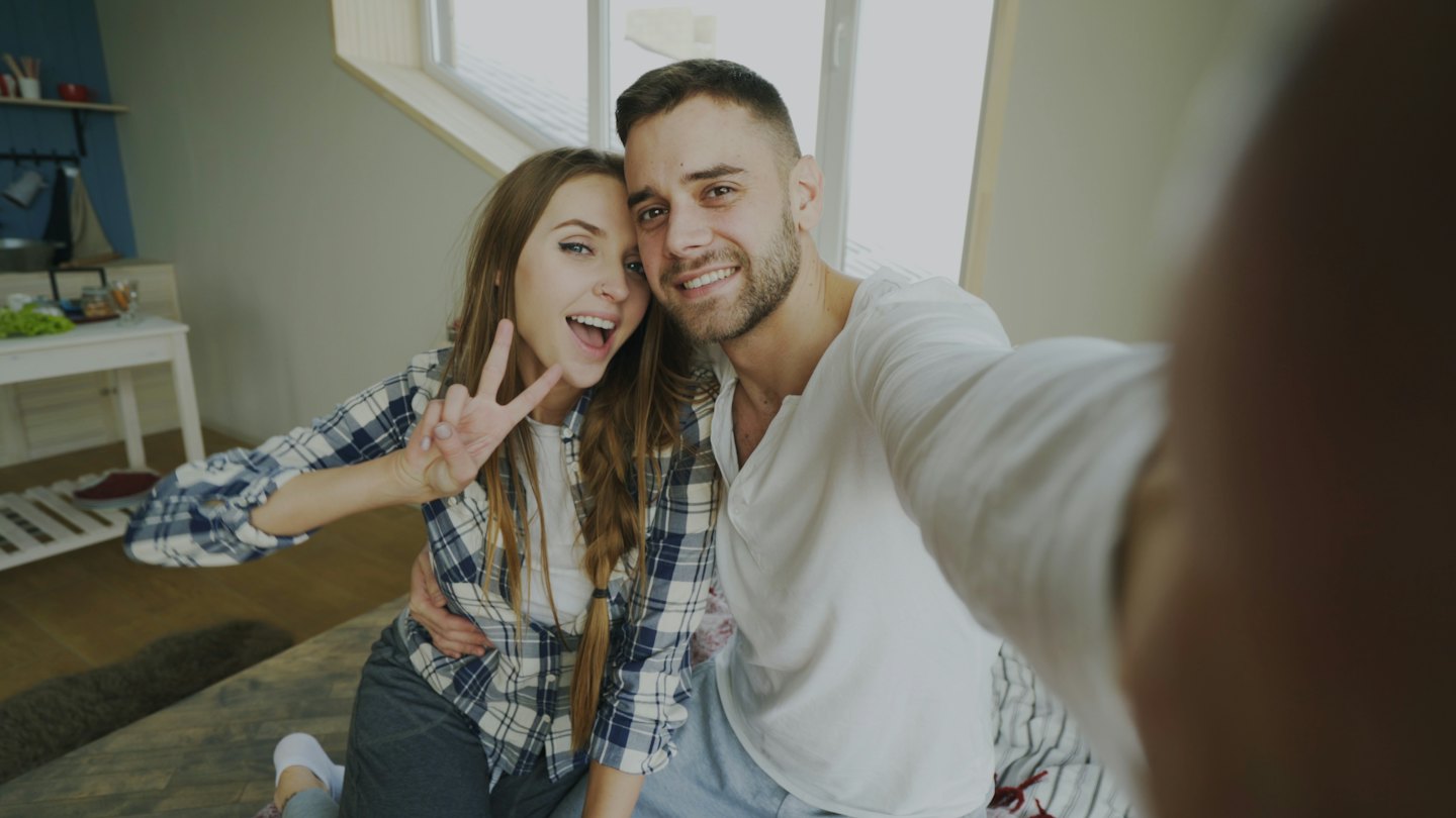 Young couple taking a happy selfie indoors.