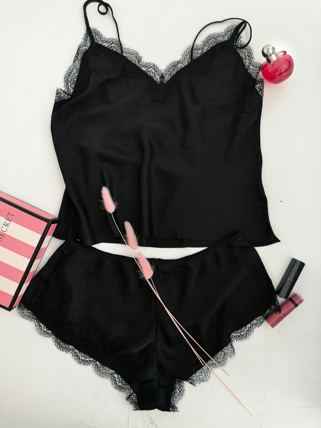 Black lace pajamas arranged with perfume and makeup accessories.