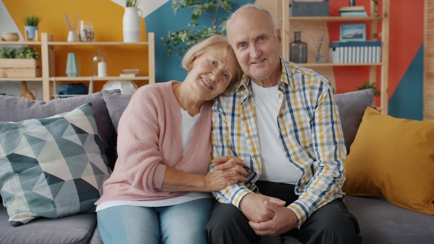 Couple holding hands on a sofa in a living room.