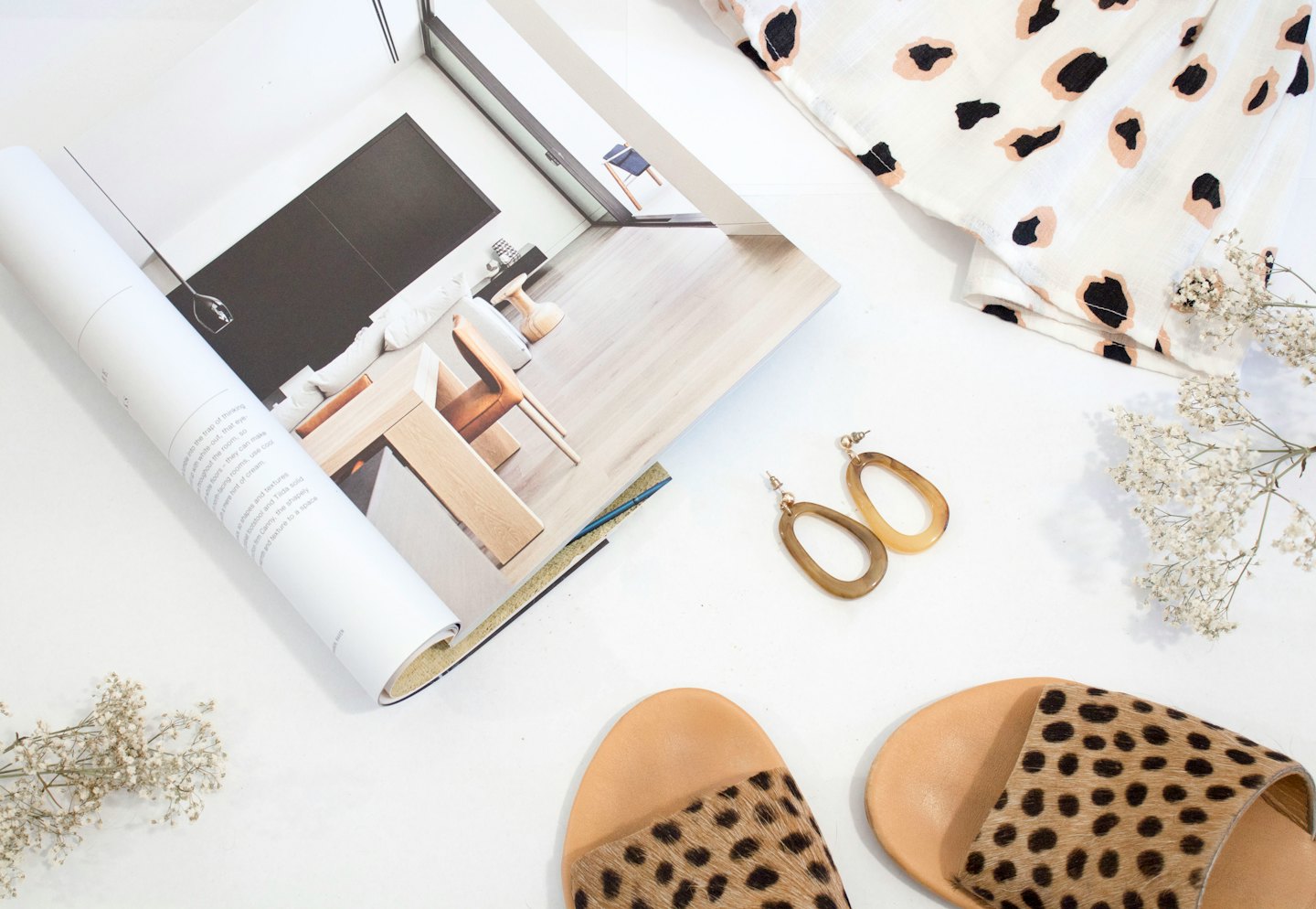 Flat lay of magazine, animal print top, leopard slides, and earrings.