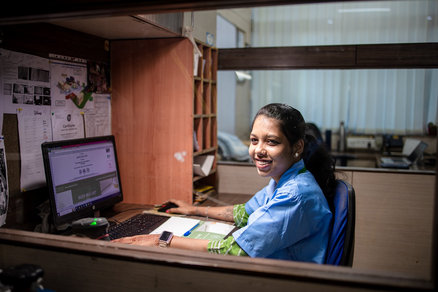 Woman in blue uniform working at her office computer.
